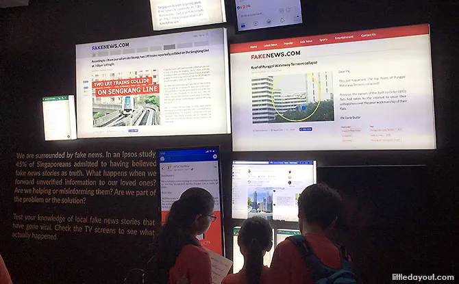 Visitors at a wall of fake news screens