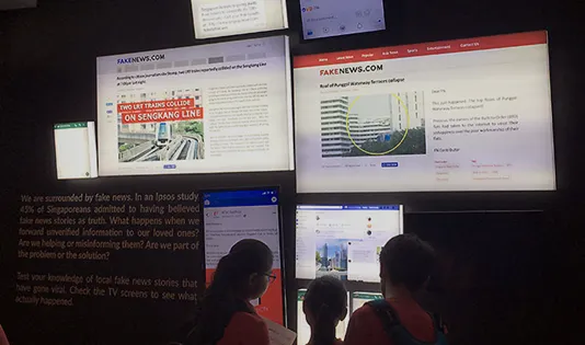 Visitors reading fake news examples on screens