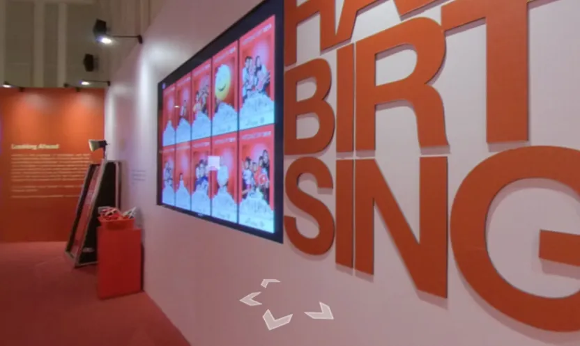 Happy Birthday Singapore lettering beside a wall of screens
